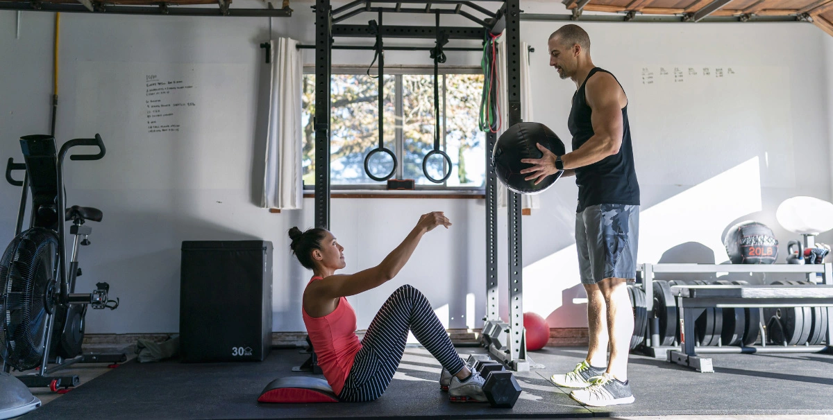 woman and man working out with a weight ball