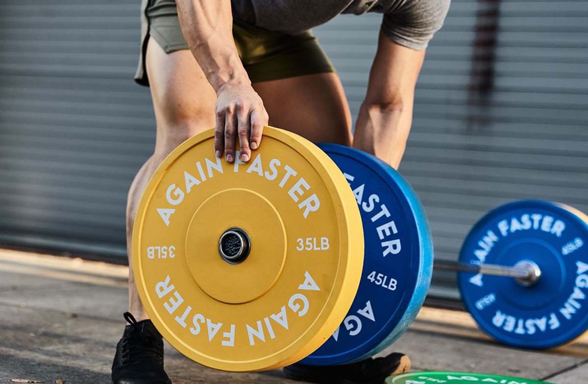 man adding bumper plate to barbell