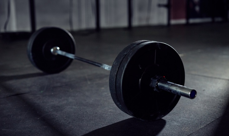 A barbell and bumper plates on the floor in a gym