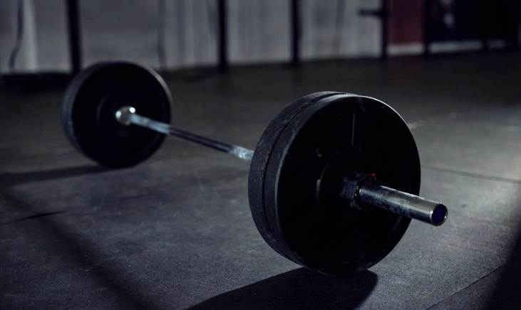 how-can-barbell-sumo-deadlifts-boost-your-training A barbell and bumper plates on the floor in a gym