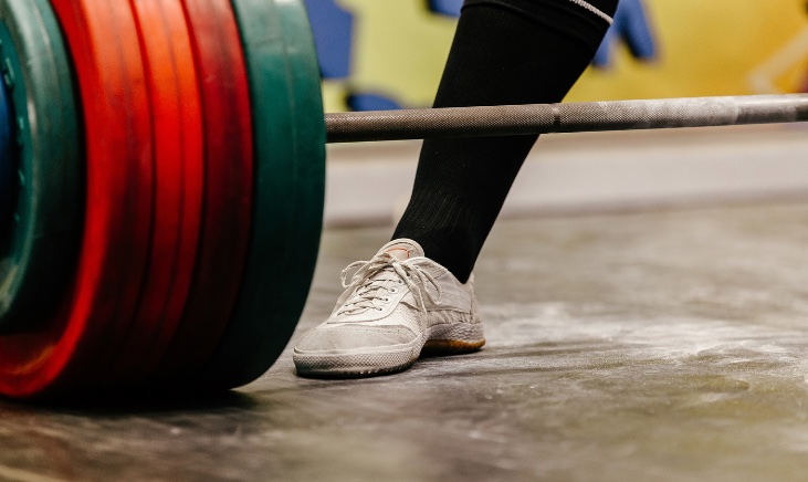 Person standing behind a barbell with weight plates